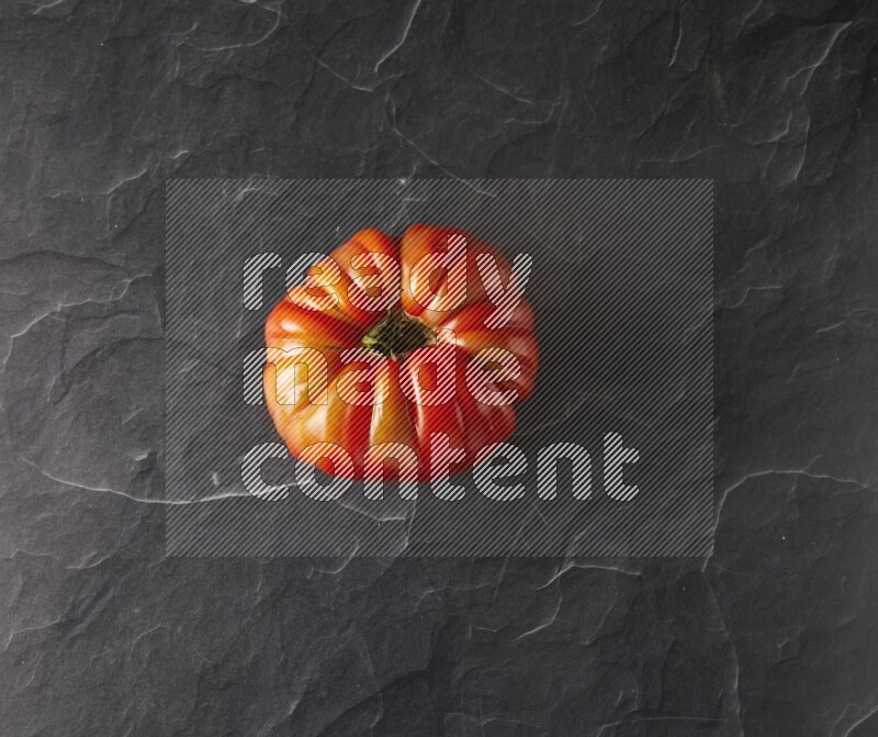 Single Topview Heirloom tomato on a black slate background