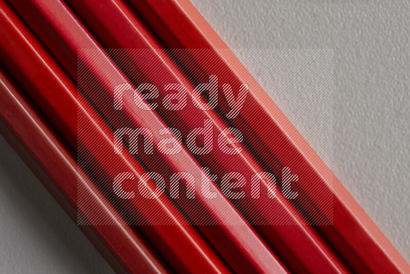 A collection of sharpened colored pencils arranged showcasing a gradient of red hues on grey background