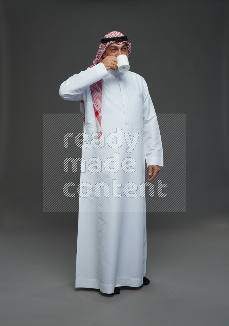 Saudi man with shomag Standing holding mug on gray background