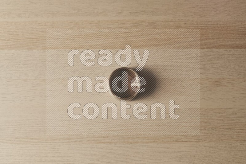A brown pottery bowl on light wooden background