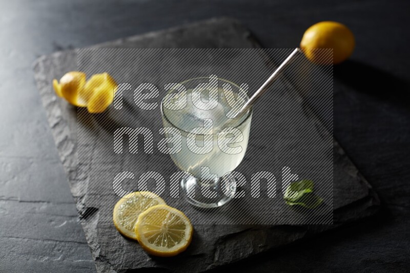 A glass of lemon juice with a straw on black background