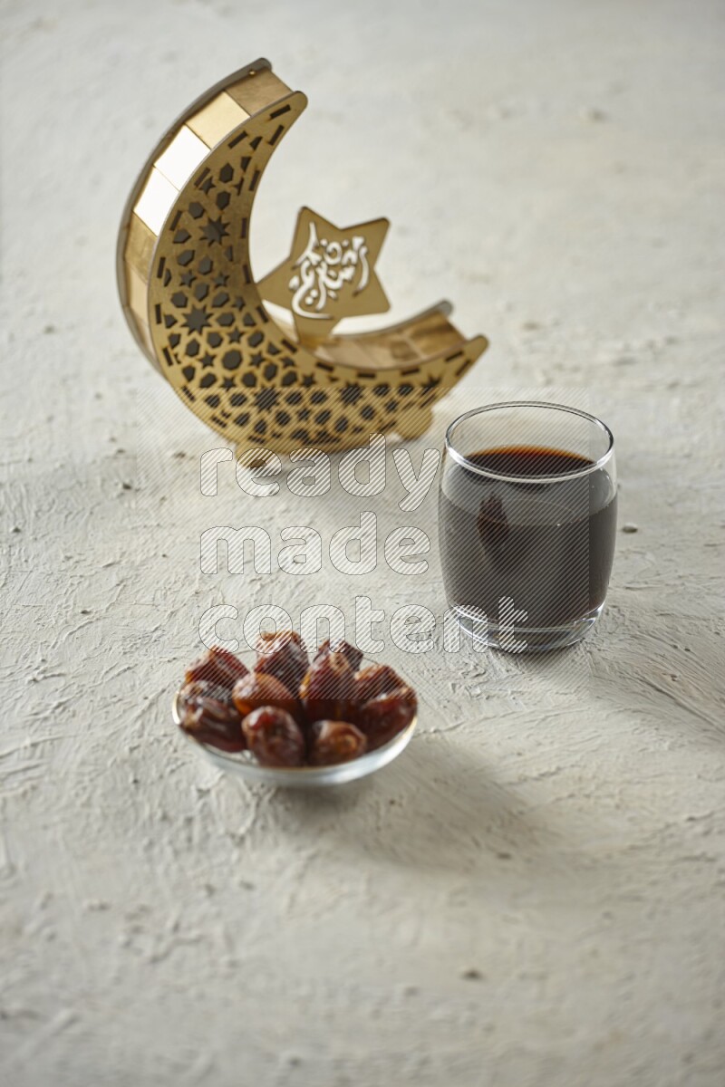 A wooden golden crescent lantern with different drinks, dates, nuts, prayer beads and quran on white background