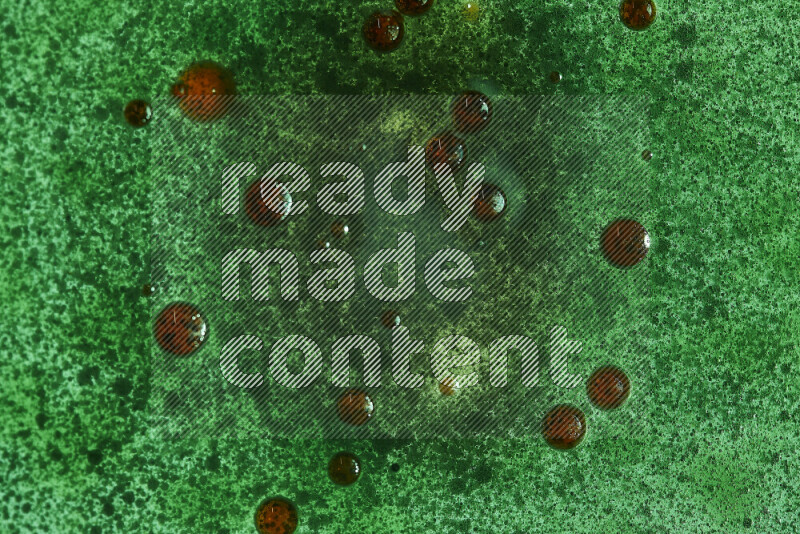 Close-ups of abstract red and green watercolor drops on oil Surface on green background