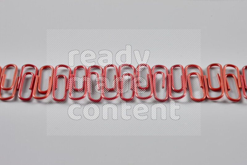 Red paper clips isolated on a grey background