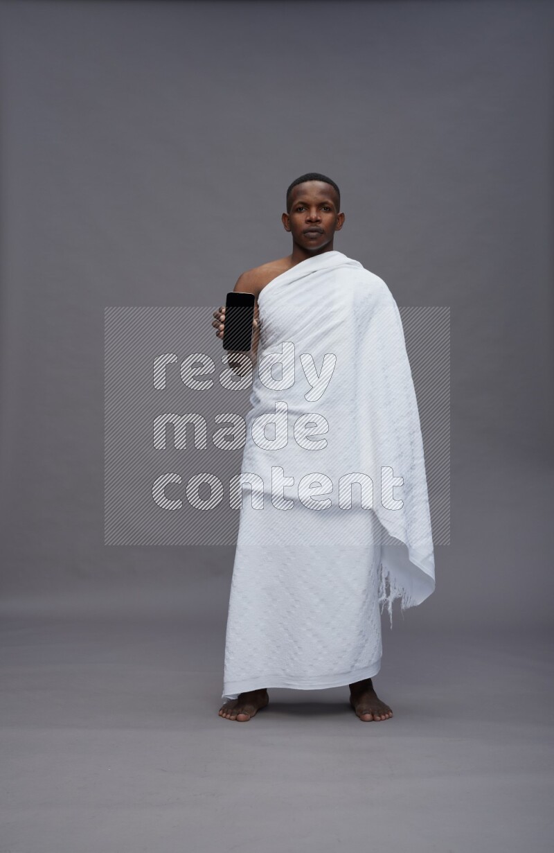A man wearing Ehram Standing showing phone to camera on gray background
