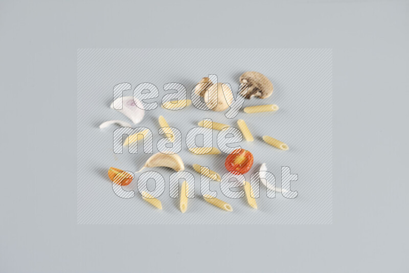 Raw pasta with different ingredients such as cherry tomatoes, garlic, onions, red chilis, black pepper, white pepper, bay laurel leaves, rosemary, cardamom and mushrooms on light blue background