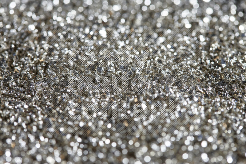 Silver shimmering fragments of glass scattered on a black background