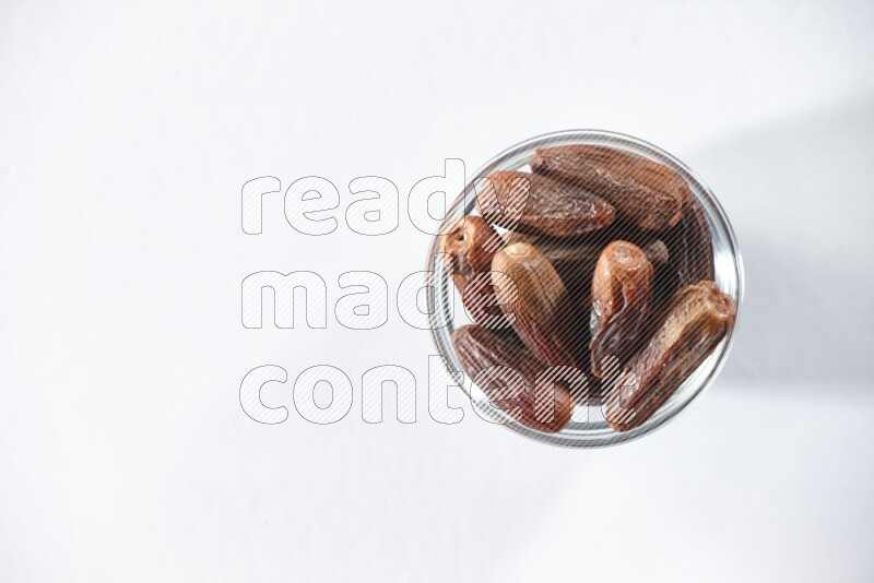 A glass bowl full of dried dates on a white background in different angles