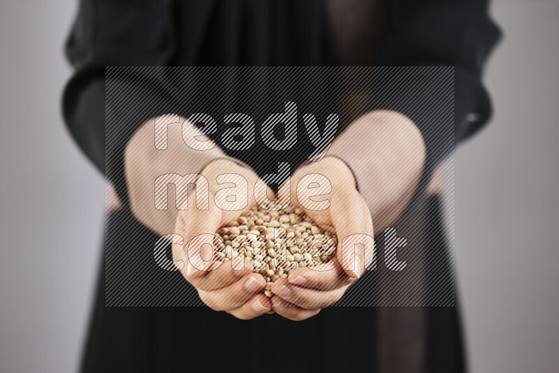 Woman in abaya holding different kinds of legumes in different positions