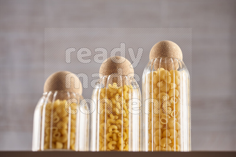 Raw pasta in glass jars on beige background