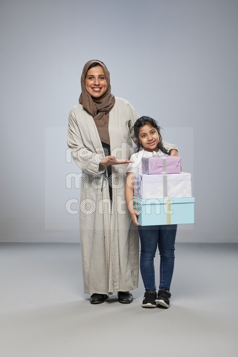 A girl giving a gift to her mother on gray background