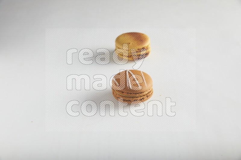45º Shot of of two assorted Brown Irish Cream, and Yellow Crème Brulée macarons on white background