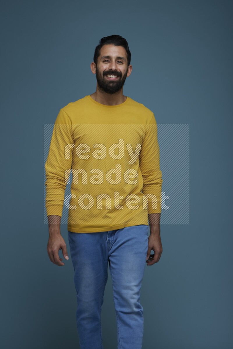 Man posing in a blue background wearing a yellow shirt