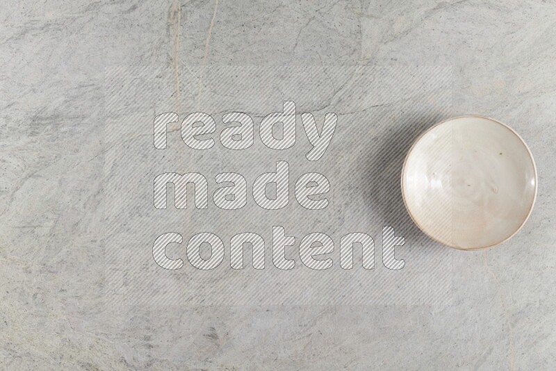 A beige pottery plate on grey marble background