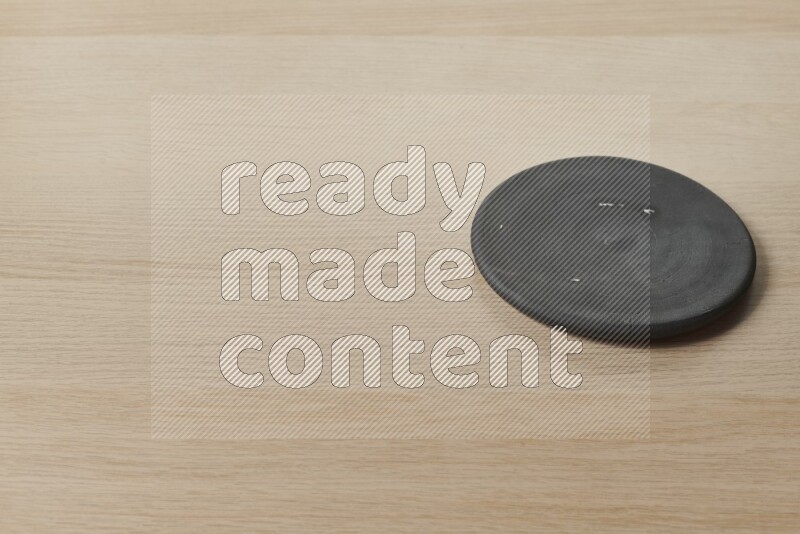 A pottery coaster on light wooden background