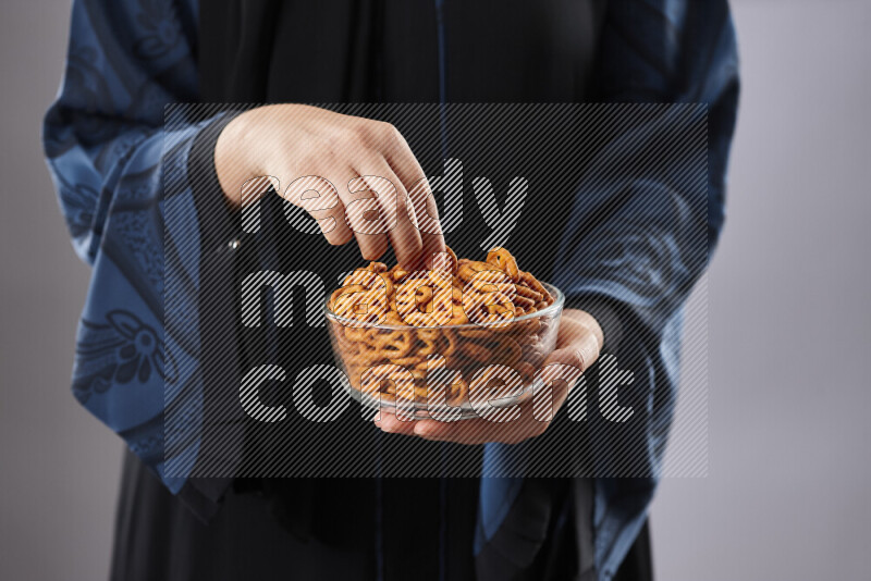 Woman in abaya holding different kinds of snacks in different positions