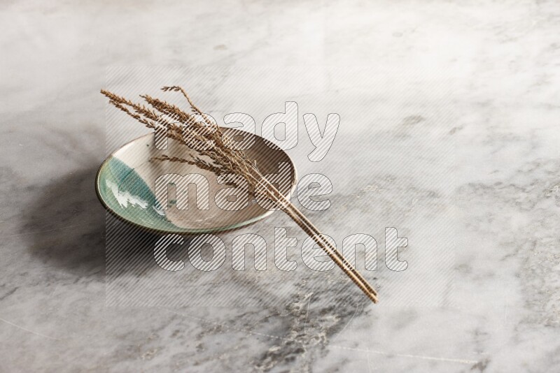 Wheat stalks on multicolored pottery plate on grey marble background