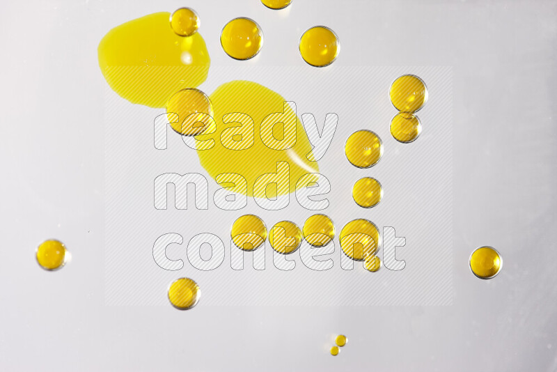 Close-ups of abstract yellow watercolor drops on oil Surface on white background