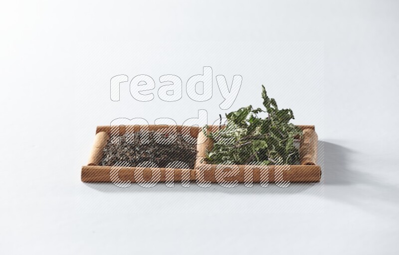 مربعان من أعواد القرفة ممتلئان بالشاي الأسود والنعناع المجفف علي خلفية بيضاء