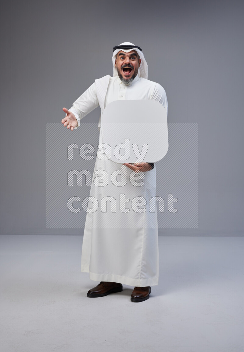 Saudi man Wearing Thob and white Shomag standing holding social media sign on Gray background