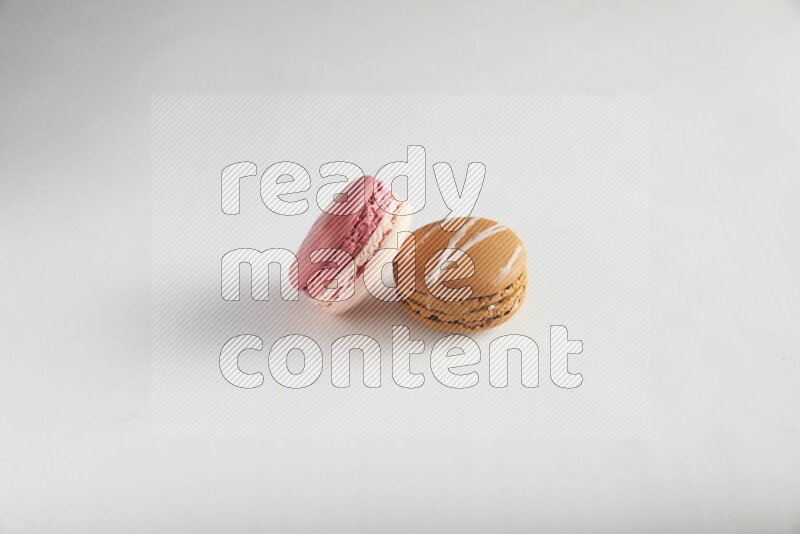 45º Shot of of two assorted Brown Irish Cream, and Pink Litchi Raspberry macarons on white background
