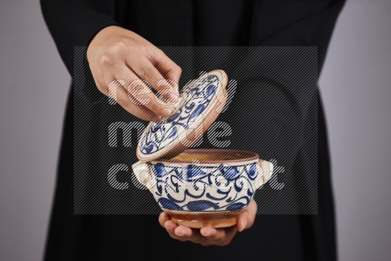 A woman in black abaya holding different pottery essentials in different positions