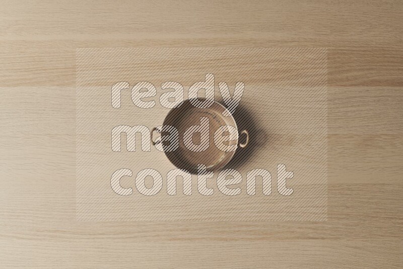 A small copper pan on light wooden background
