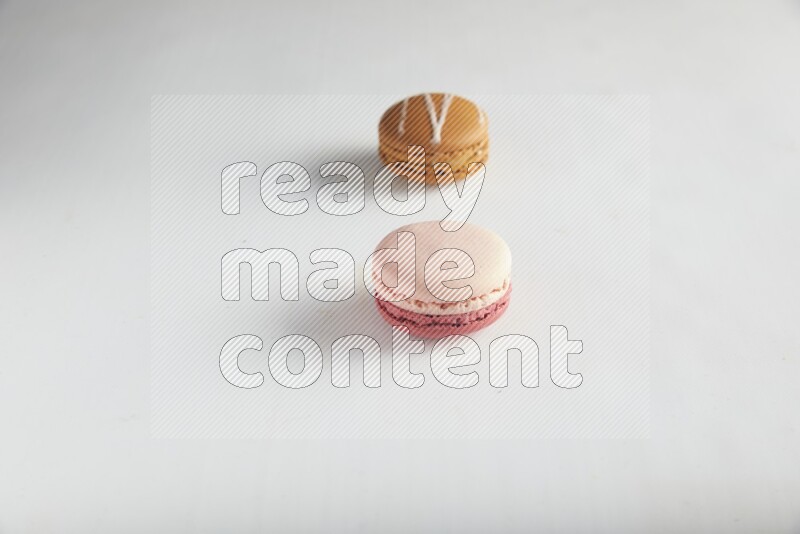 45º Shot of of two assorted Brown Irish Cream, and Pink Litchi Raspberry macarons on white background