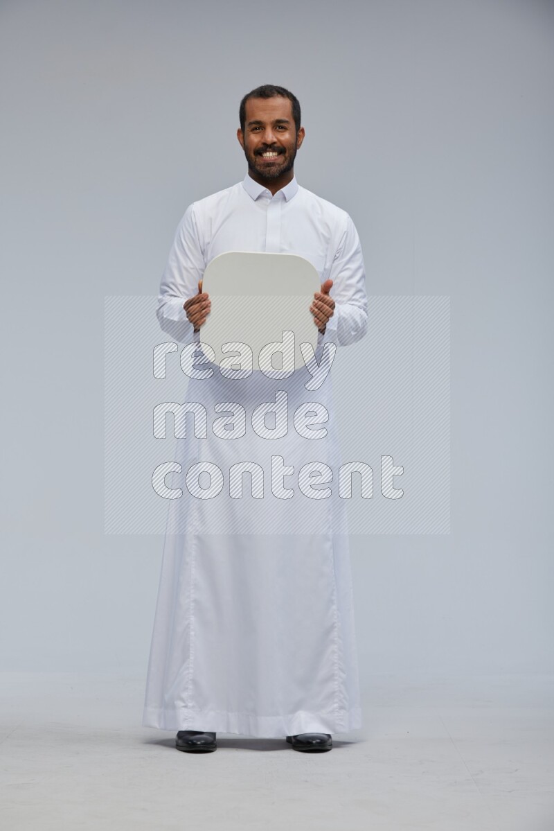 Saudi man wearing Thob standing holding social media sign on Gray background