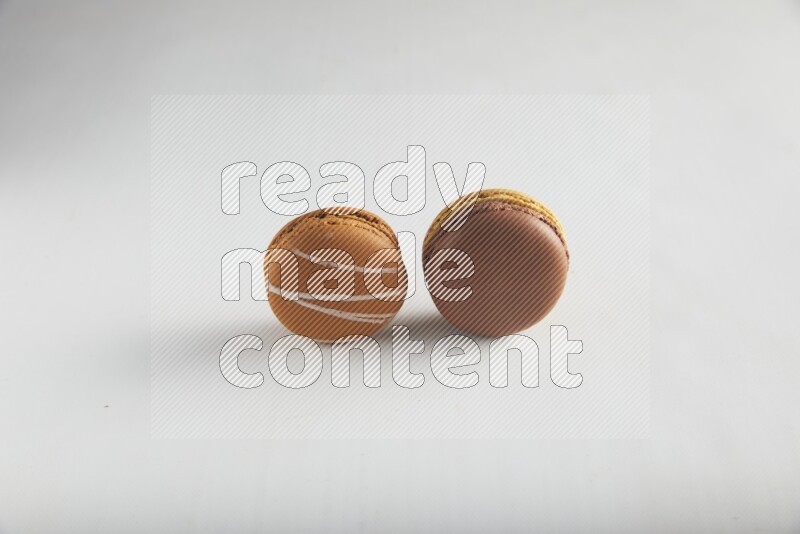 45º Shot of of two assorted Brown Irish Cream, and Yellow, and Brown Chai Latte macarons on white background