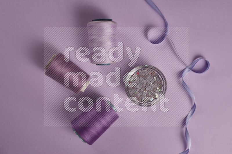 A purple collection of sewing and tailoring tools arranged on a purple background