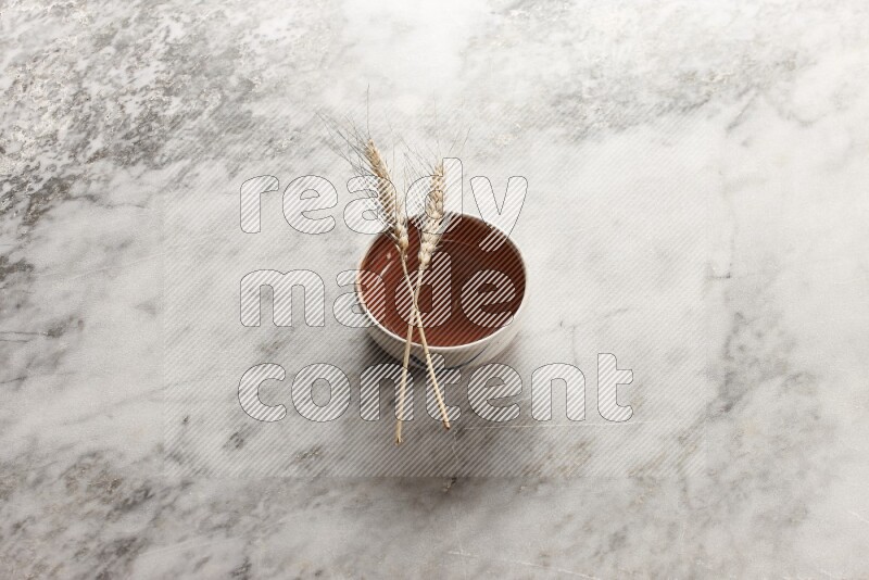 Wheat stalks on brown pottery bowl on grey marble background