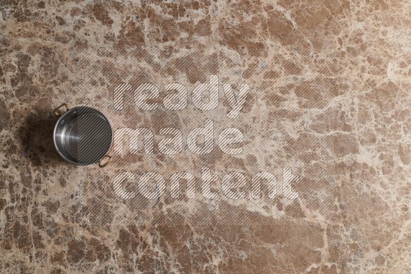 A small copper pot on beige marble background