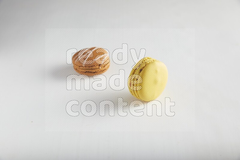 45º Shot of of two assorted Brown Irish Cream, and Yellow Lemon macarons on white background