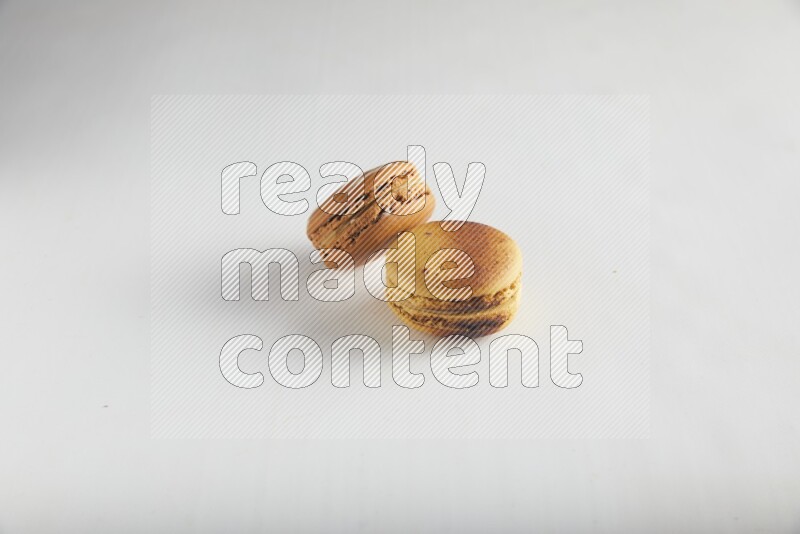 45º Shot of of two assorted Brown Irish Cream, and Yellow Crème Brulée macarons on white background