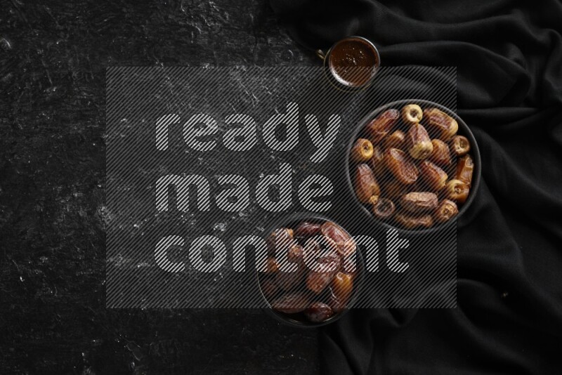 Dates in pottery bowls with coffee in a dark setup
