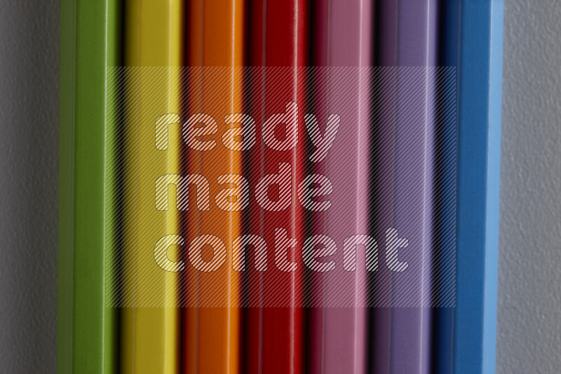 مجموعة من أقلام الرصاص الملونة مرتبة لتعرض تدرجا من الألوان المختلفة علي خلفية رمادية