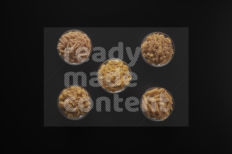 أنواع مختلفة من المعكرونة في أوعية زجاجية علي خلفية سوداء