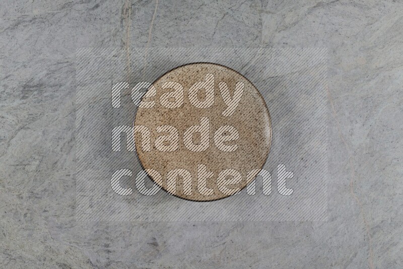 A beige pottery plate on grey marble background
