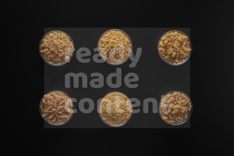 أنواع مختلفة من المعكرونة في أوعية زجاجية علي خلفية سوداء