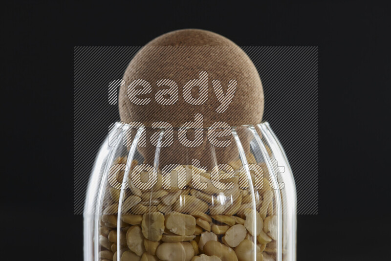 Crushed beans in a glass jar on black background