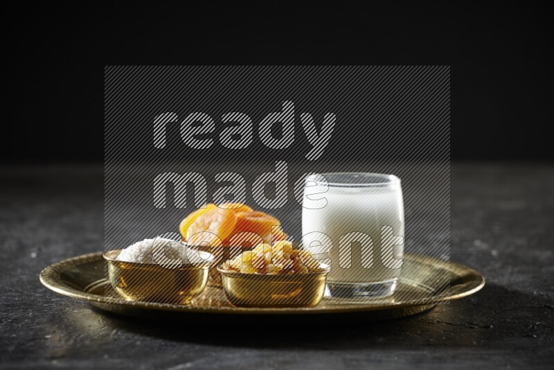 Dried fruits in metal bowls with sobya on a tray in dark setup