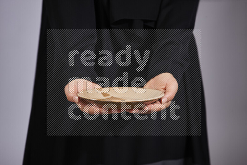 A woman in black abaya holding different pottery essentials in different positions
