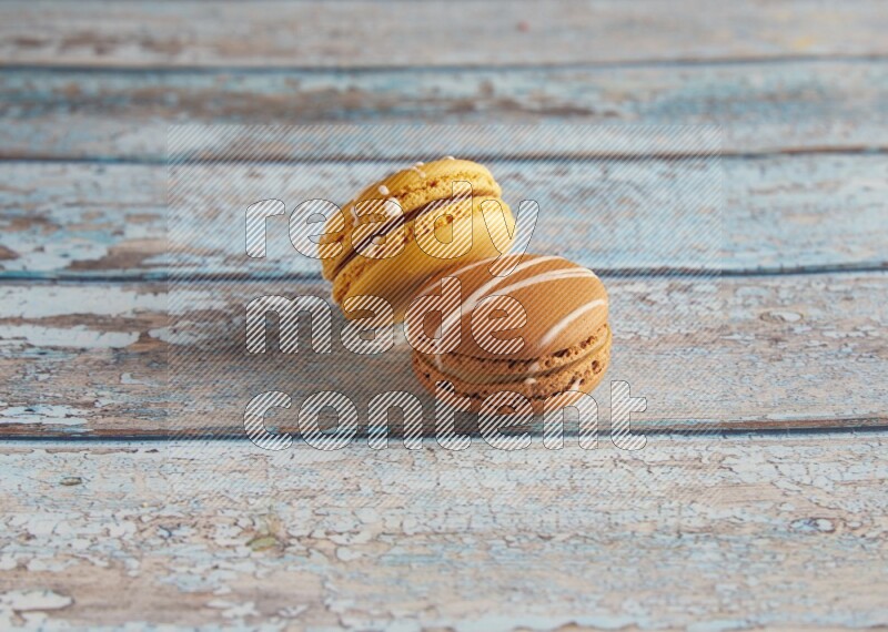 45º Shot of of two assorted Brown Irish Cream, and Yellow Piña Colada macarons on light blue background