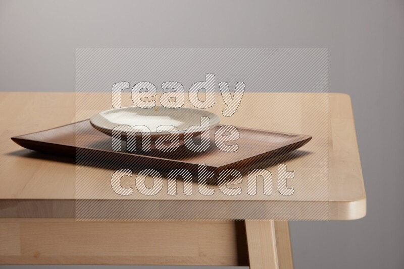 multicolored plate on a rectangular wooden tray on the edge of wooden table