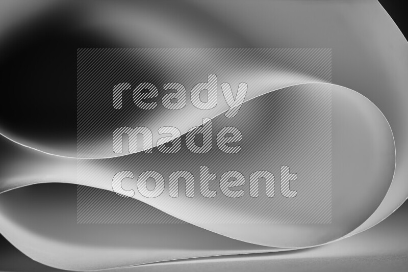 An abstract art piece displaying smooth curves in grey gradients created by colored light