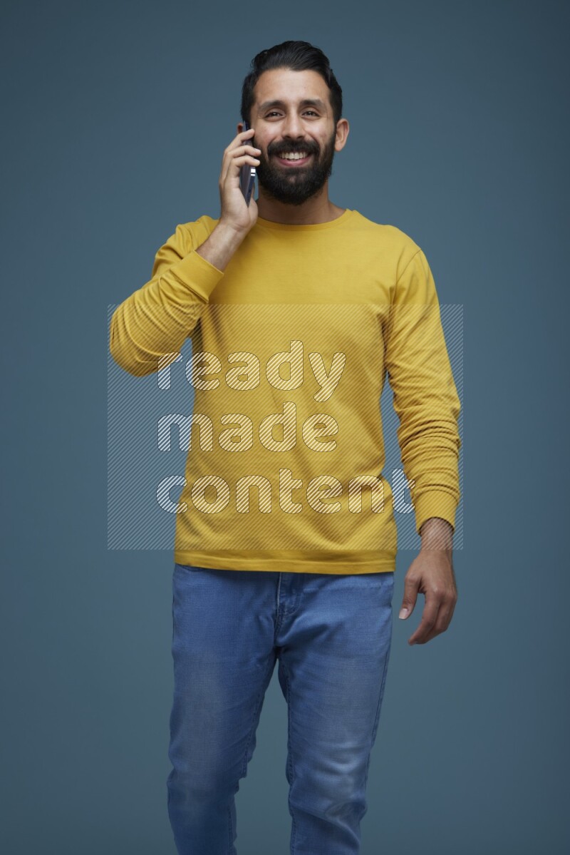 A man having a calling in a blue background wearing a yellow shirt