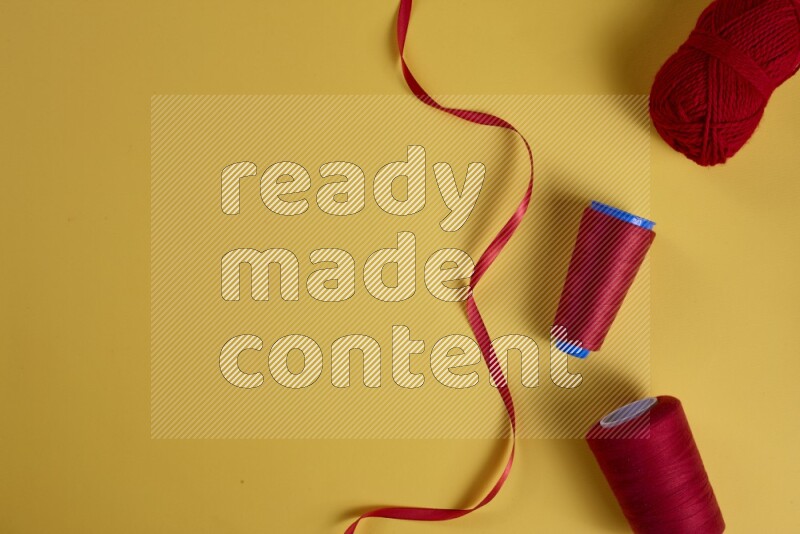 A red collection of sewing and tailoring tools arranged on a yellow background