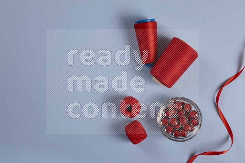 A red collection of sewing and tailoring tools arranged on a blue background