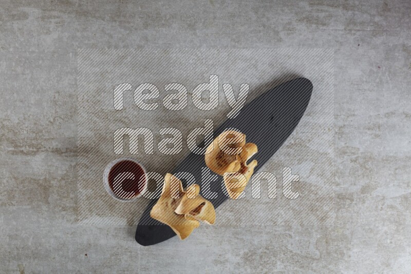 wonton cups with soy sauce ramkin on oval slate on grey textured counter top